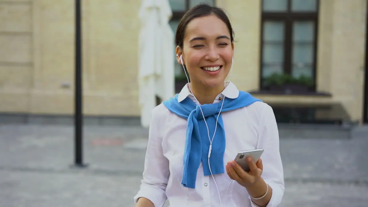 Cheerful Woman Dancing And Listening Music Walking Towards The Camera Outdoors