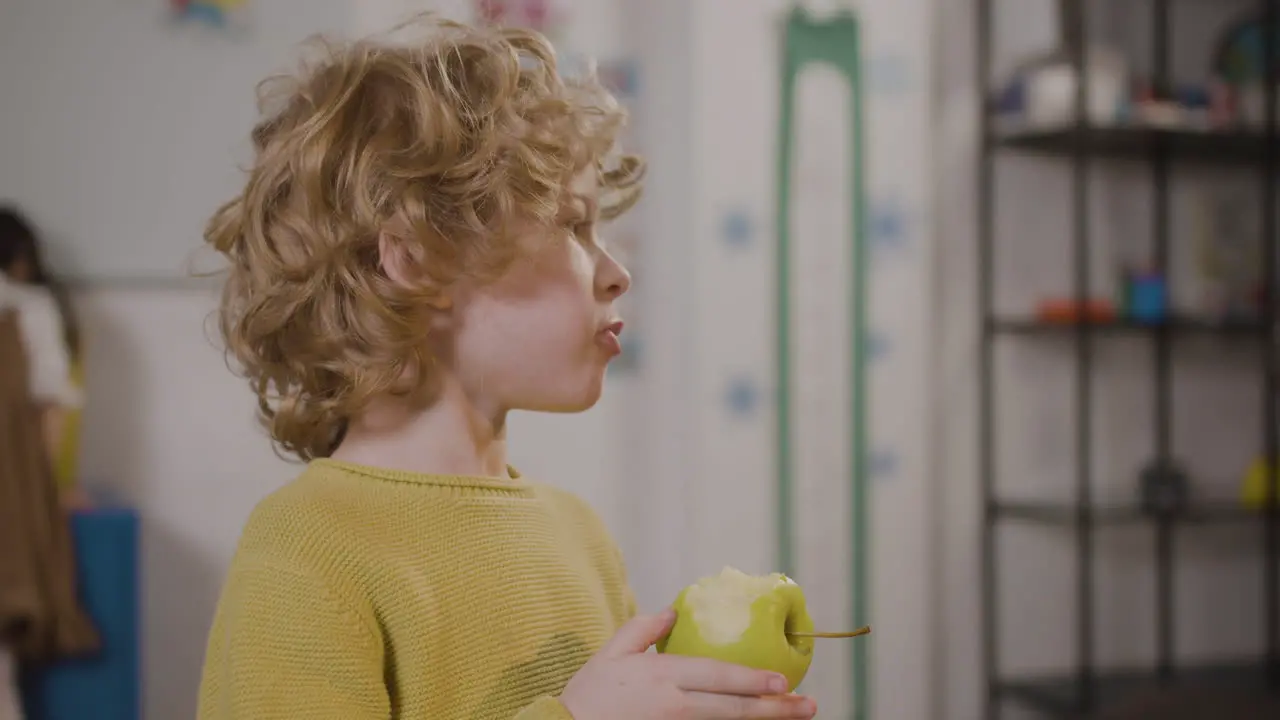 Little Boy Eating An Apple In Classroom In A Montessori School 1