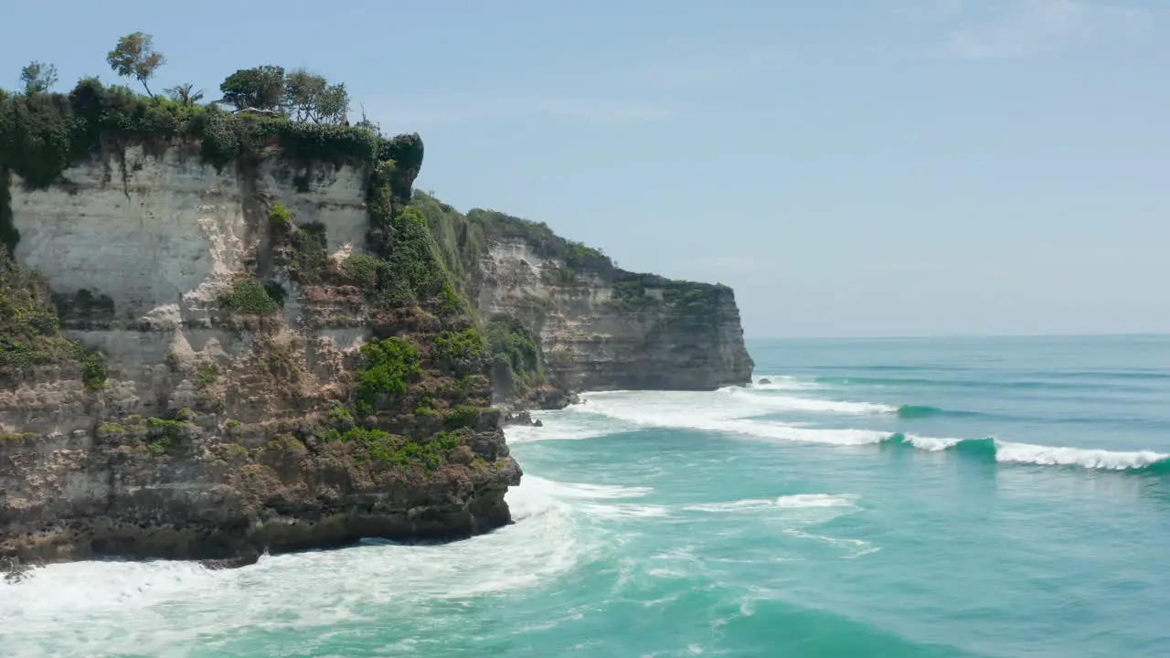 Stunning tropical coastline and blue ocean in Bali Indonesia Aerial view of large waves crashing in rocky cliffs in Bali