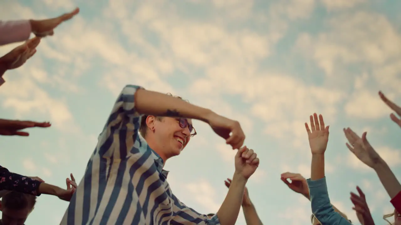 Partying people raising hands up outdoors Excited man dancing at party