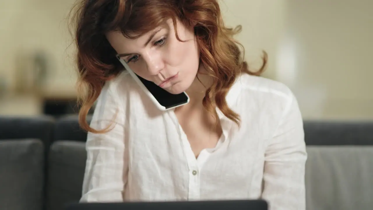 Smiling woman sitting with laptop at workplace Business woman talking by phone