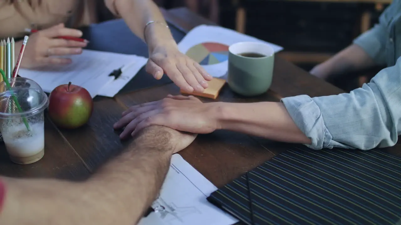 Business people putting their hands on each other on table for teamwork