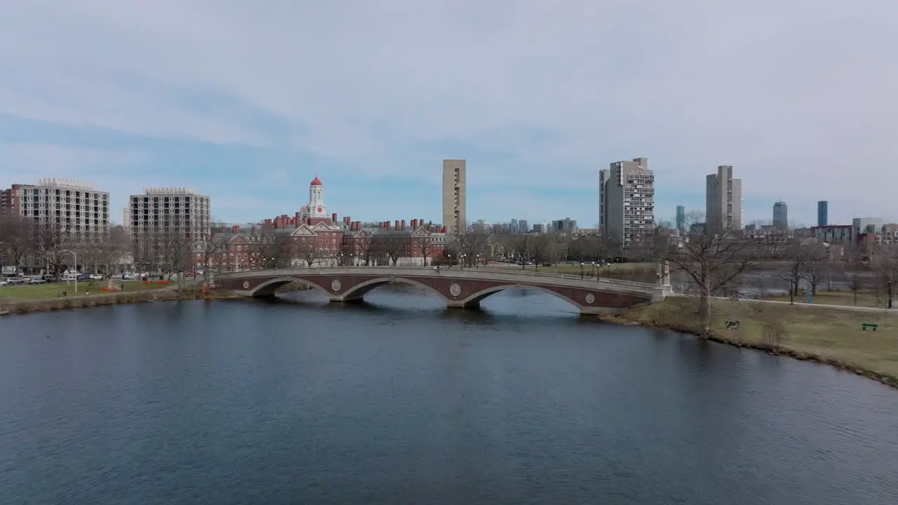 Forwards fly above water surface towards John W Weeks Footbridge over Charles river Dunster House in background Boston USA