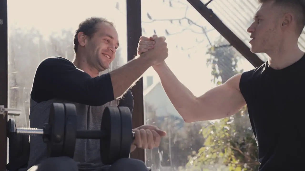 Disabled Man In Wheelchair Working Out With Dumbbell At Home While His Personal Trainer Motivating Him 1