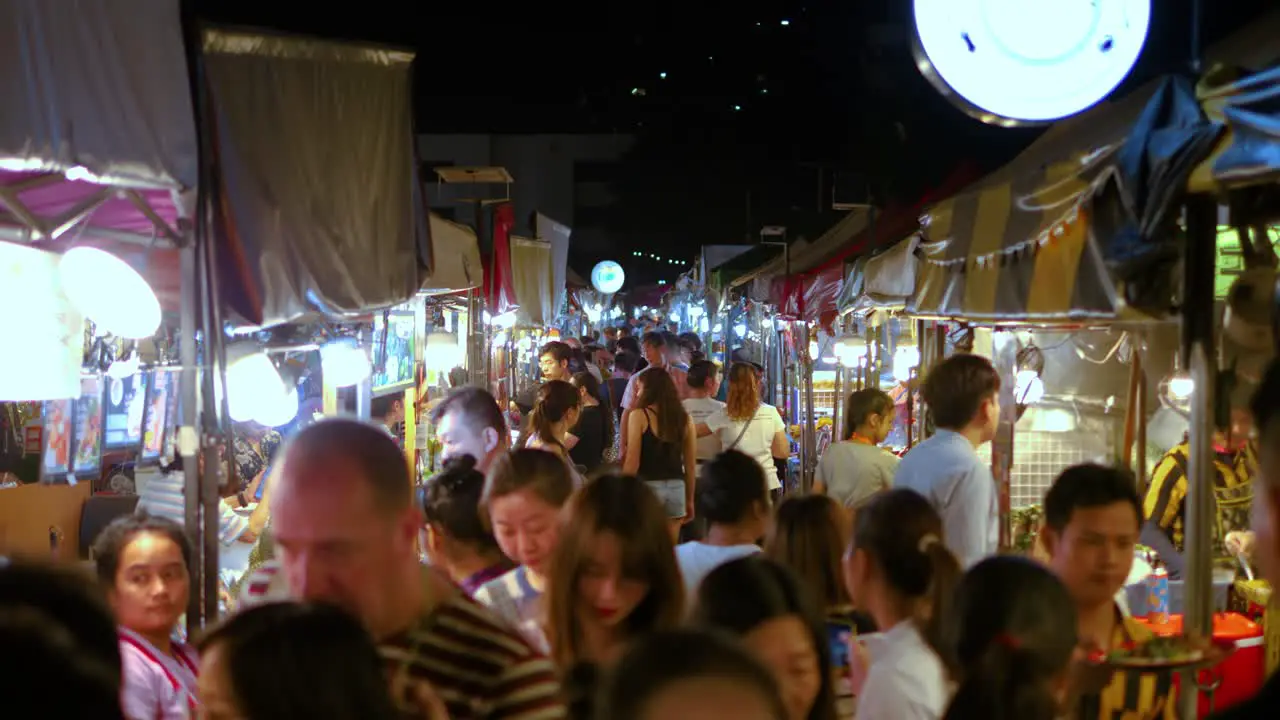 Moving through Crowded night market food stalls in slowmotion Bangkok