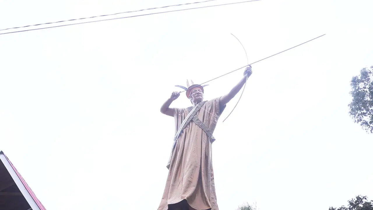 Daytime revolving shot around the sculpture of a Shipibo local archer aiming in Oxapampa Peru