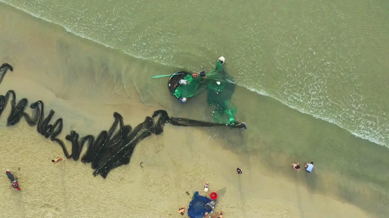 drone view fishermen is pulling fishing net to the basket boat on My Khe beach by Da Nang city