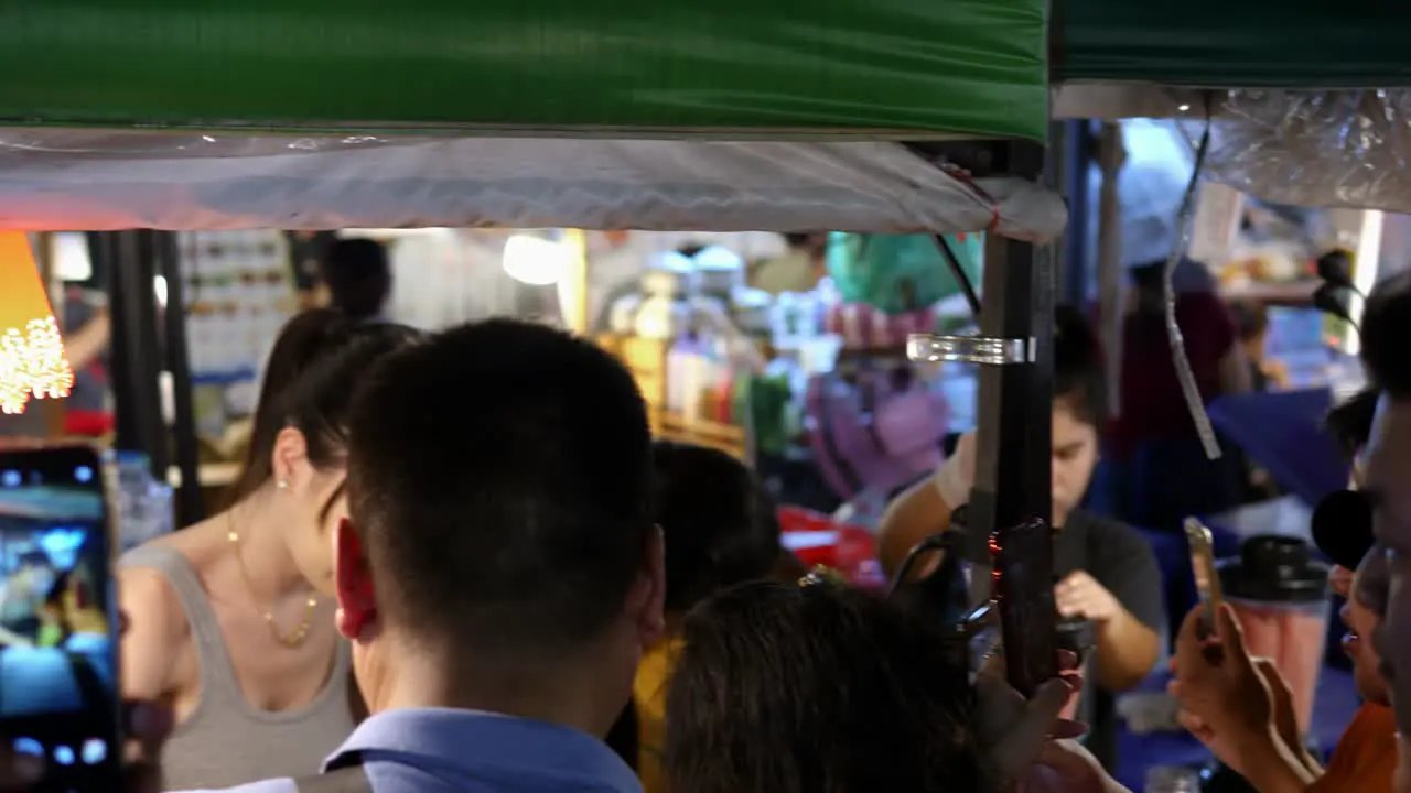 Group of people recording beautiful hot woman on street food market stall Thailand