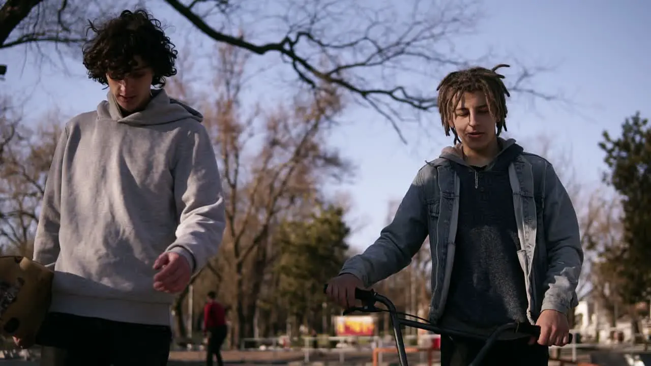 Two Friends Skateboarder And Bmx Rider Are Walking Together In The City Skate Park