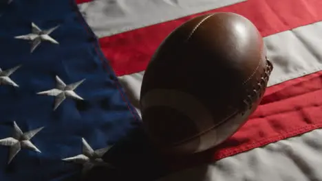 Low Key Lighting Studio Shot Of American Football On Stars And Stripes Flag 9