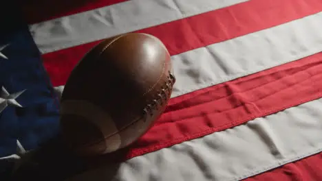 Low Key Lighting Studio Shot Of American Football On Stars And Stripes Flag 10