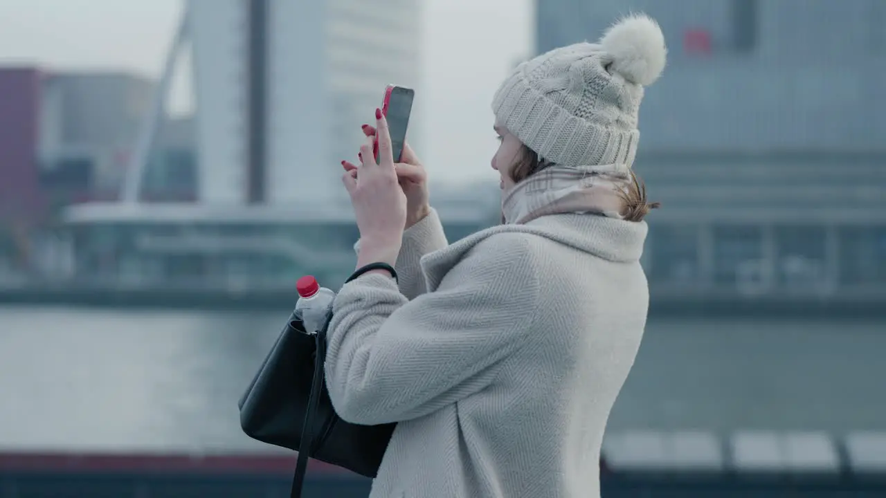 Female tourist taking pictures of the city of Rotterdam on a cold and overcast day