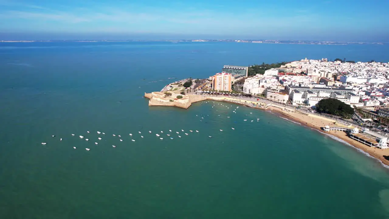 Sailboats anchored on the coastline of the white city of Cadiz Spain aerial view