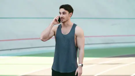 Sport man call mobile phone standing on track outdoor Fitness man talking phone