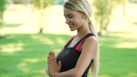 Smiling woman practicing yoga exercise in summer park Fitness a lifestyle