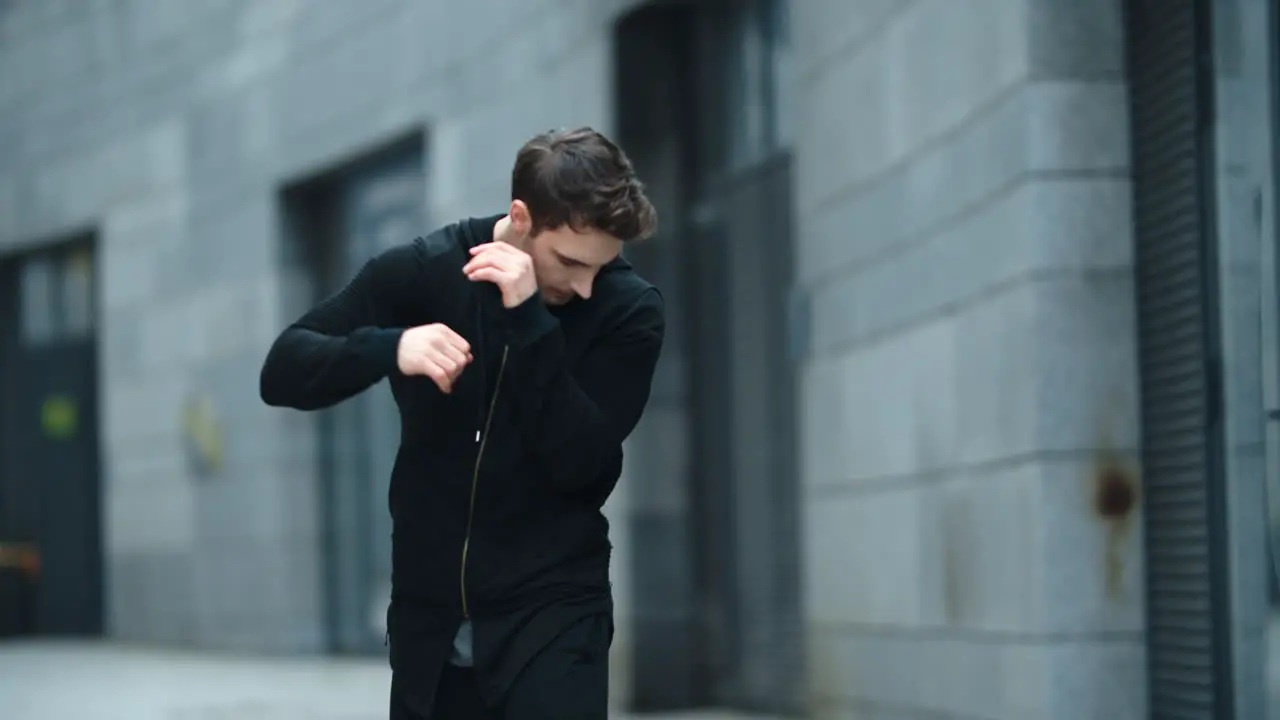 Athlete man doing warm up exercise for arms outdoor Fighter training hand kick