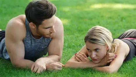 Sport people relaxing after outdoor training Man and woman lying on green grass