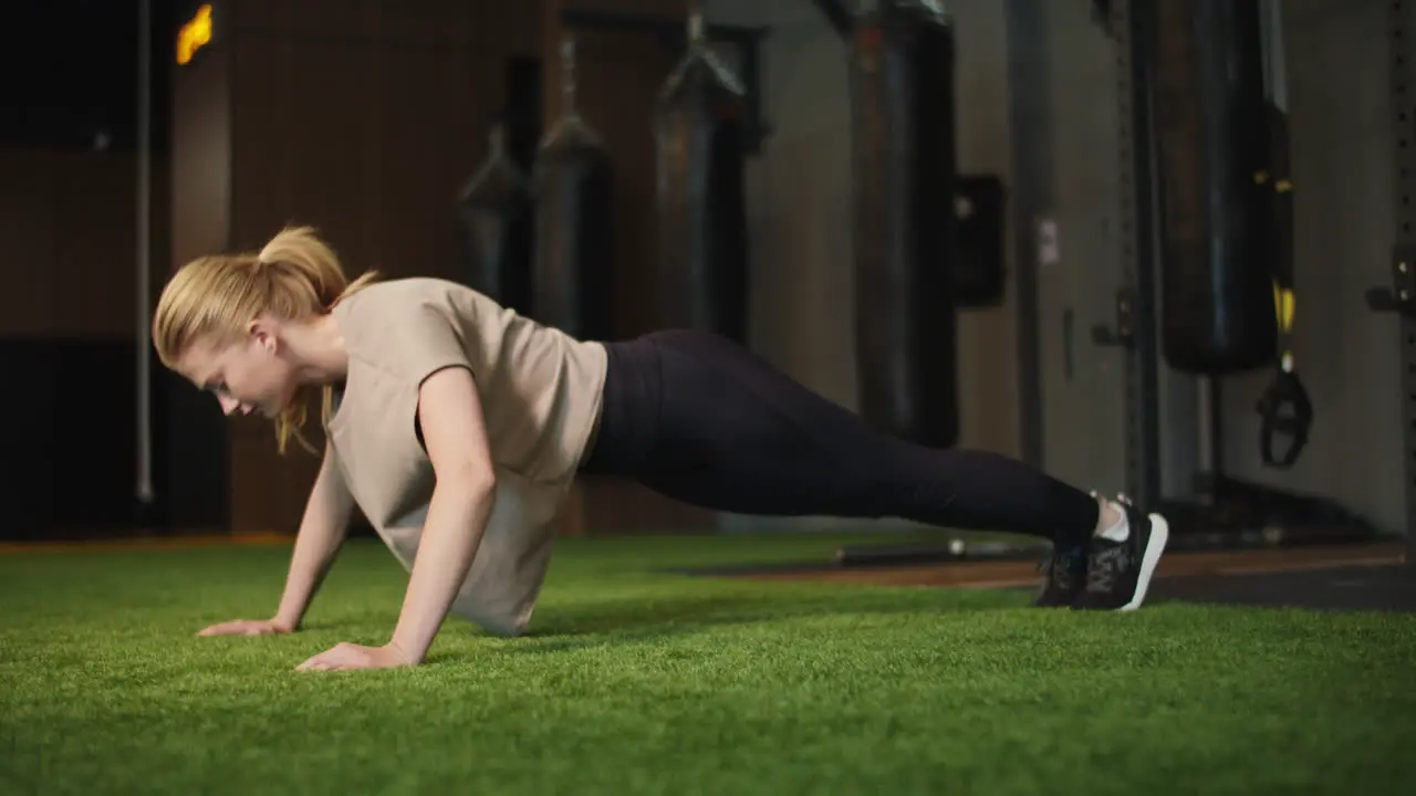 Active female boxer doing pushups in sport club Fit girl warming up at gym