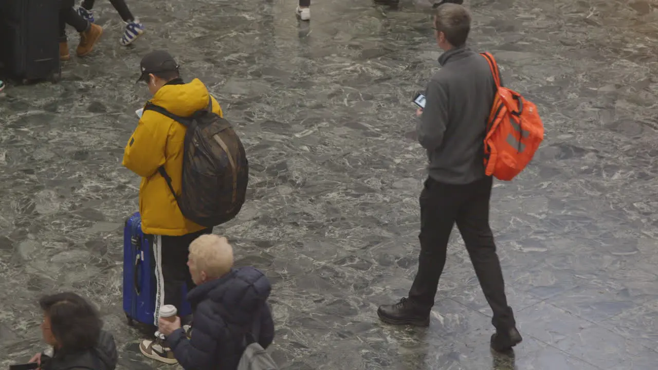 Man looks phone as people walk past