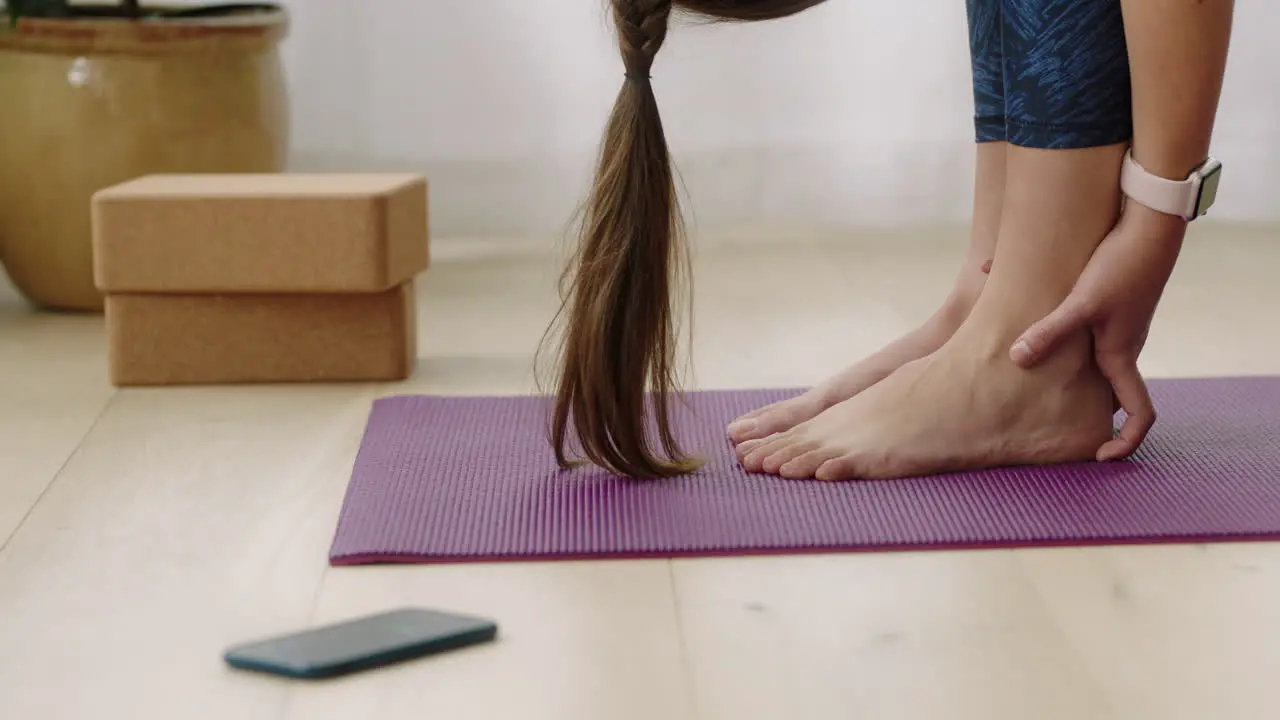 attractive yoga woman exercising healthy lifestyle practicing standing forward bend pose enjoying workout at home training on exercise mat