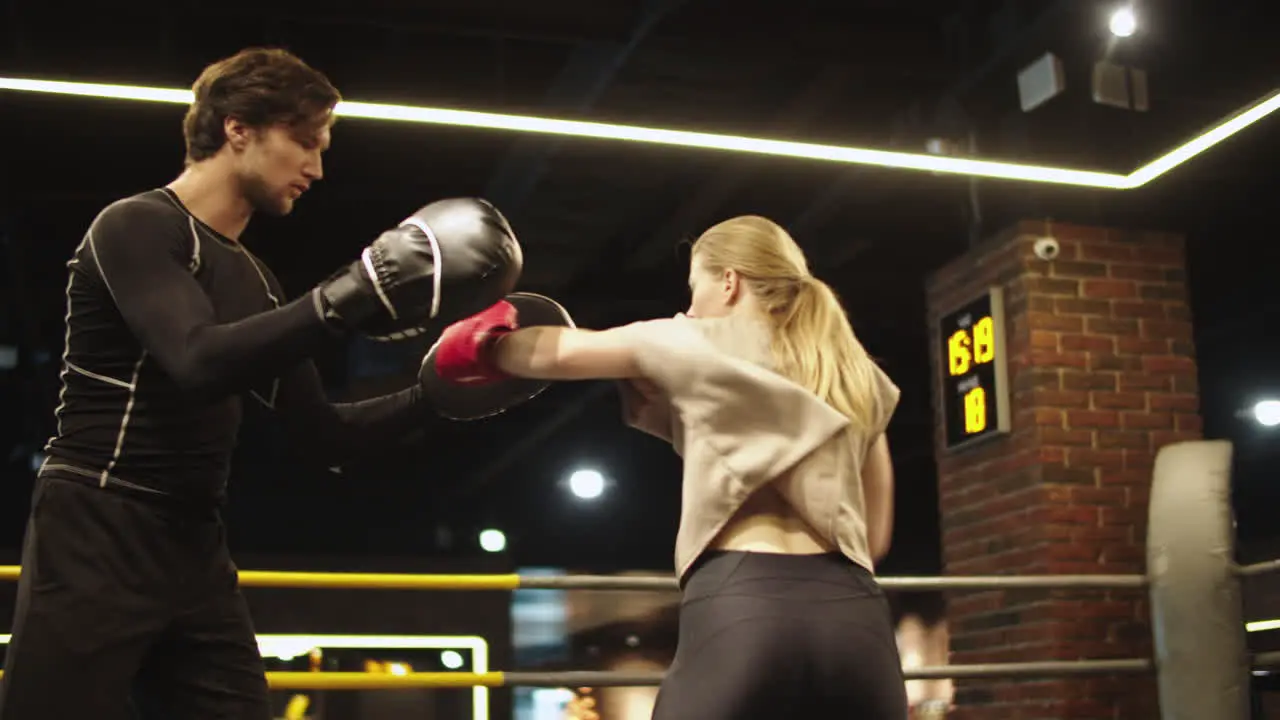 Angry sport woman training with coach at gym Fit girl fighting on boxing ring