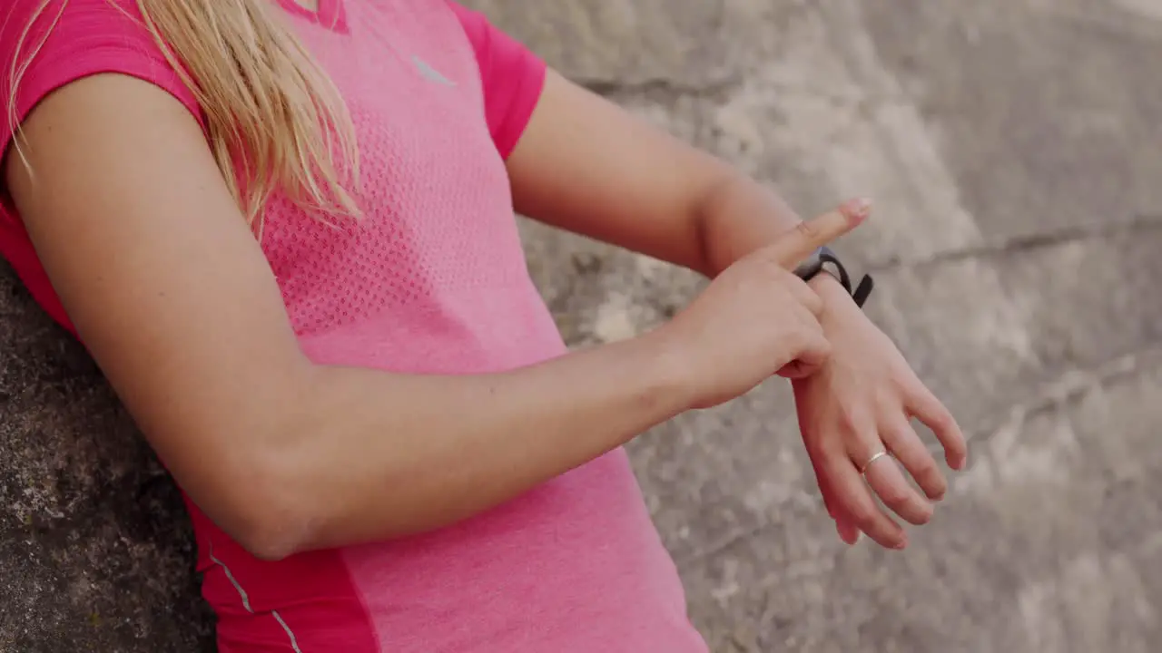 Woman looking at her watch against a wall