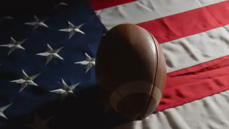 Low Key Lighting Studio Shot Of American Football On Stars And Stripes Flag 7