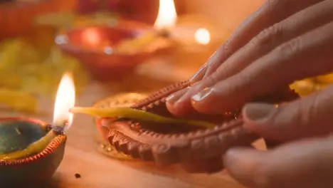 Close Up Of Person Adding Oil And Lighting Lamp Celebrating Festival Of Diwali