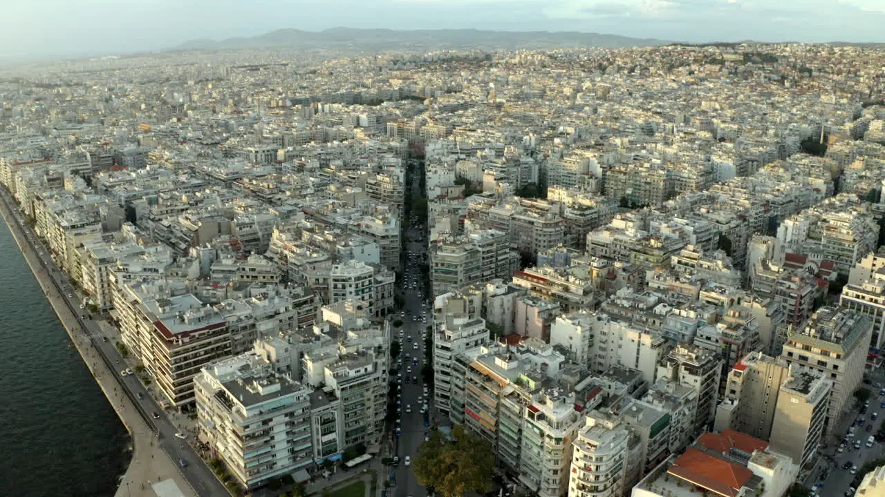 cinematic drone aerial footage flying over the northern Greece city of Thessaloniki at sunset following a main road in 4k