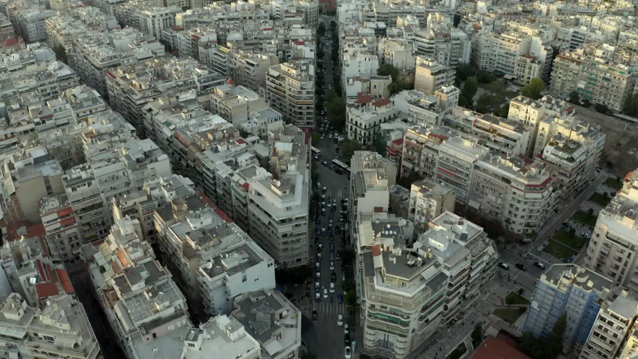 cinematic panning up aerial drone shot from topdown to showing the northern greek city of Thessaloniki at sunset following the central road in 4k