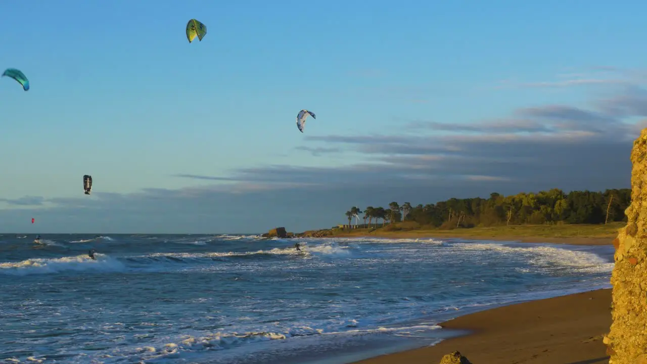 A group of people engaged in kitesurfing in sunny autumn day high waves Baltic Sea Karosta beach in Liepaja wide shot