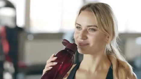 Thirsty woman enjoying water after fitness training in gym