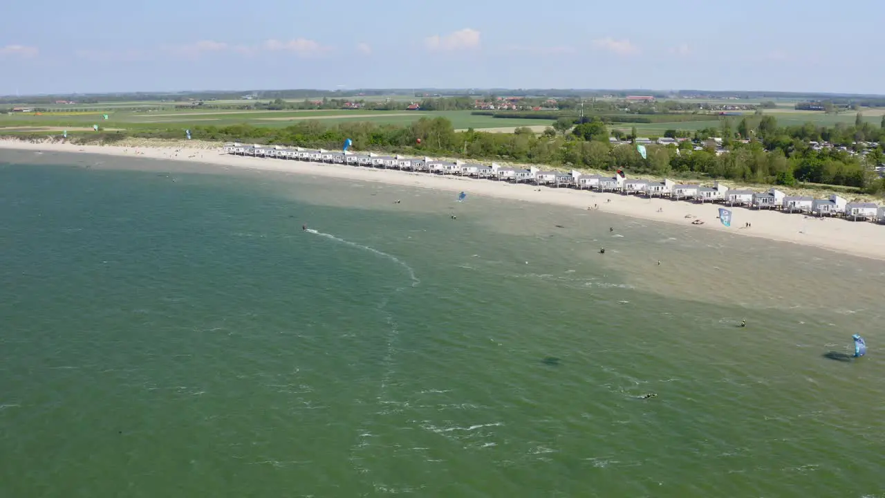 Aerial orbit over the beach near Wissenkerke the Netherlands on a windy day with many kitesurfers riding on the wind