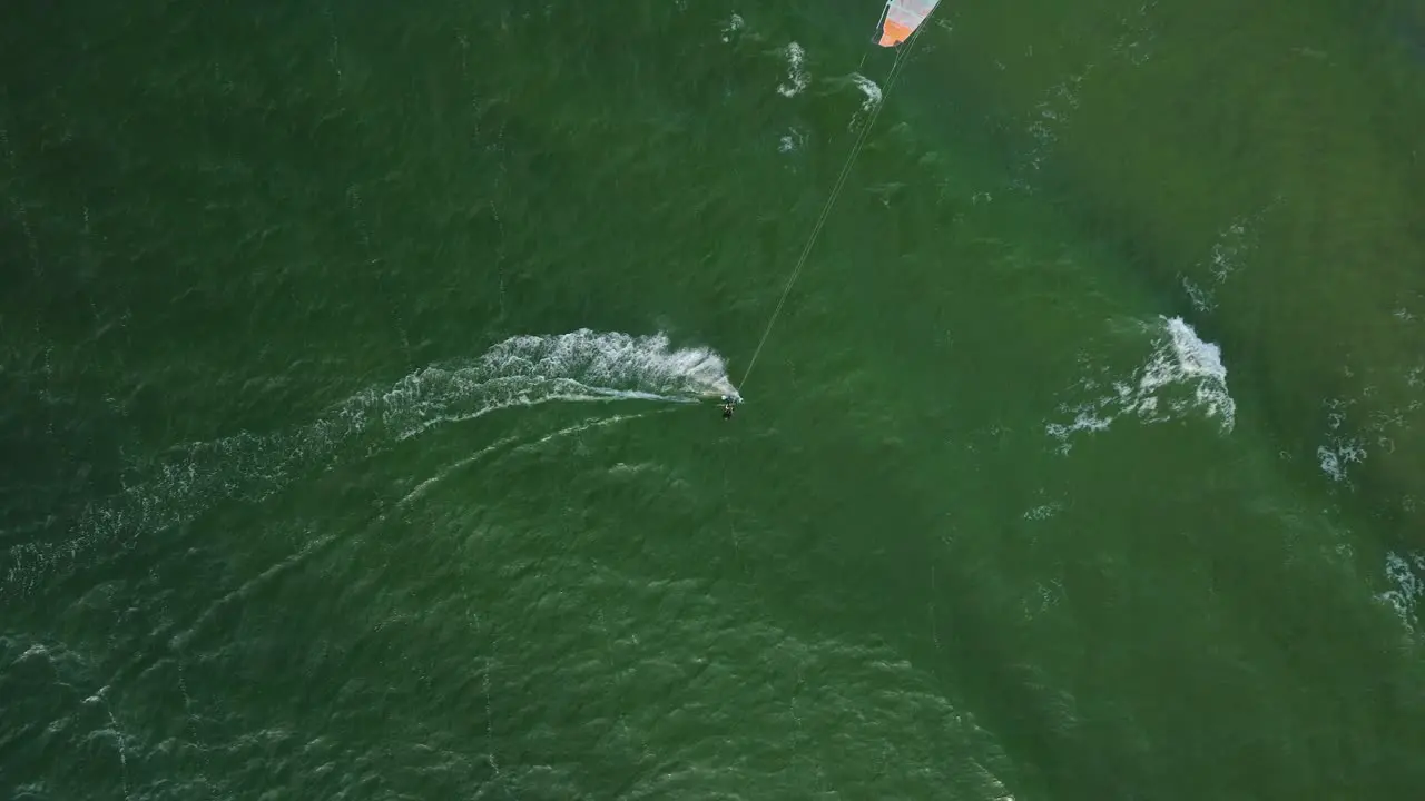 Establishing aerial view of a group of people engaged in kitesurfing sunny summer day high waves extreme sport Baltic Sea Karosta beach  birdseye drone dolly shot moving right