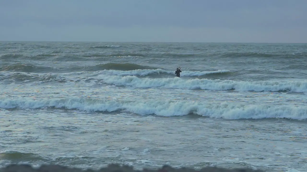 Man engaged in kitesurfing overcast winter day high waves Baltic Sea Karosta beach  slow motion distant shot