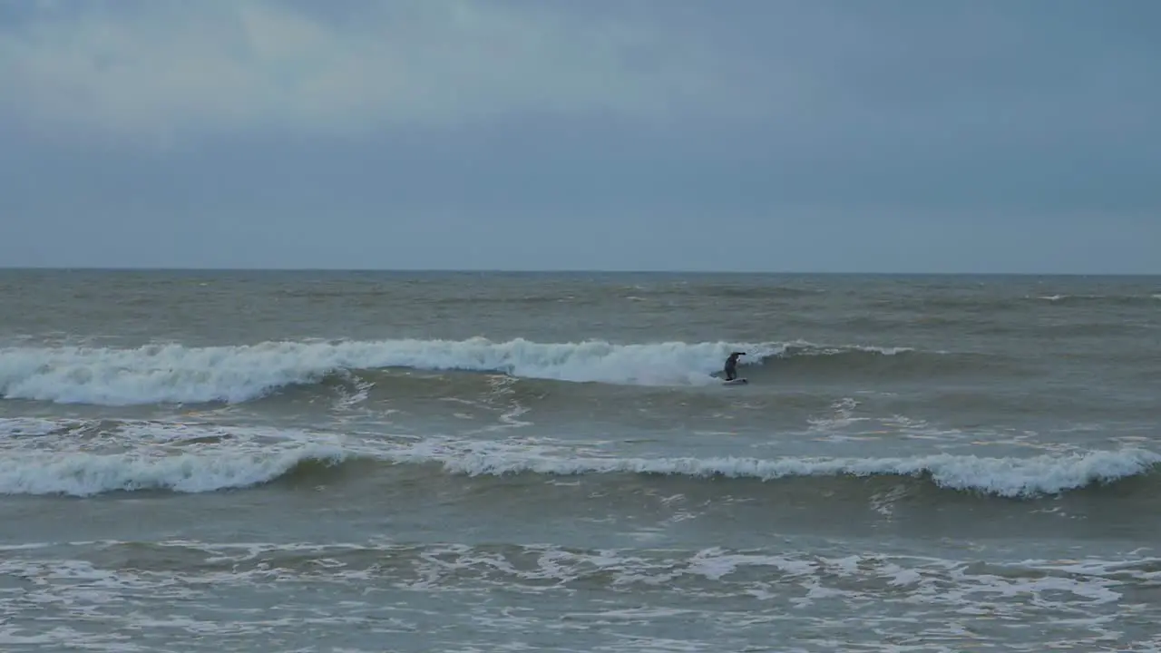 Man engaged in kitesurfing overcast winter day high waves Baltic Sea Karosta beach  slow motion wide shot