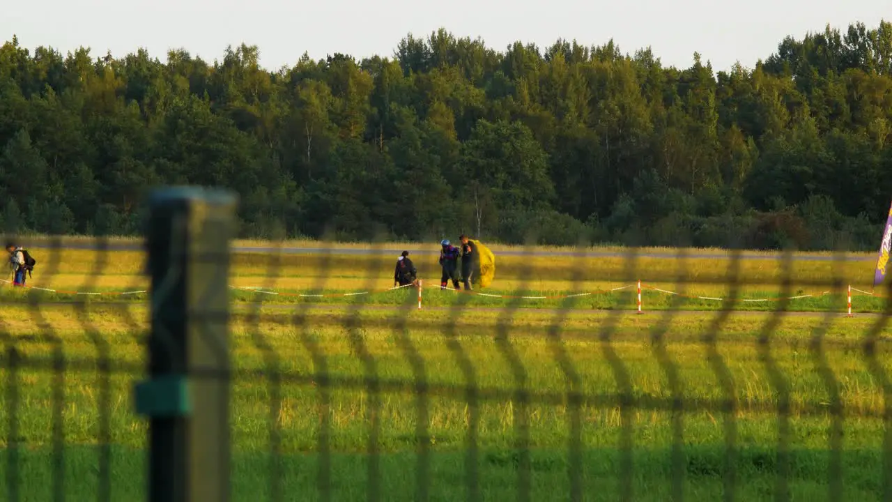 Professional skydivers taking their parachutes after a successful high altitude jump sunny summer evening medium distant shot