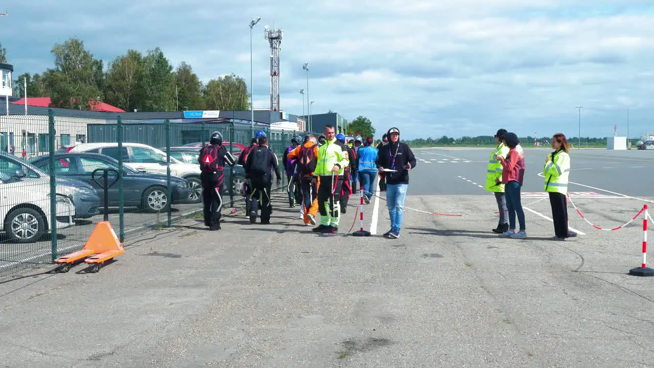 Group of professional skydivers in jumpsuits preparing for a high altitude parachute jump sunny summer day medium distant shot