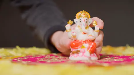 Hand Putting Down Statue Of Ganesh On Table Decorated For Celebrating Festival Of Diwali 1