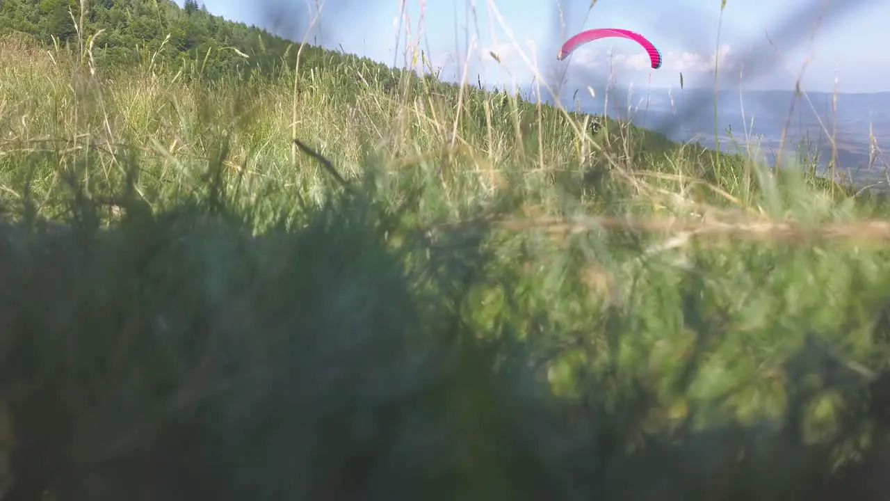 Paraglider flying left to right toward valley below