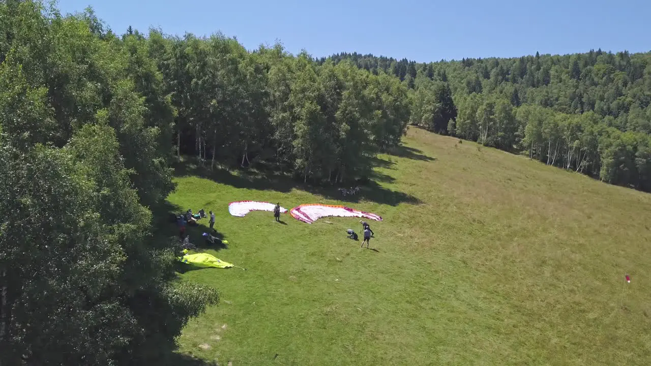 Paragliders standing on the side of a hill waiting for the wind to intensify