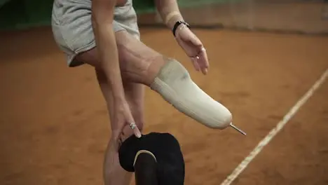 Injured beautiful brave woman athlete puts the prosthesis on the right leg standing on the tennis court Close up