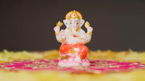 Hand Picking Up Statue Of Ganesh From Table Decorated For Celebrating Festival Of Diwali