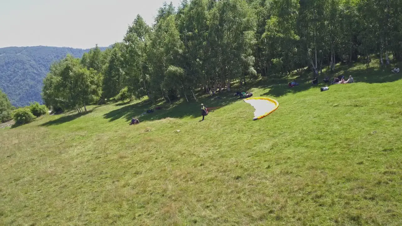 An adventurer stands on the launch site preparing for flight while paragliding