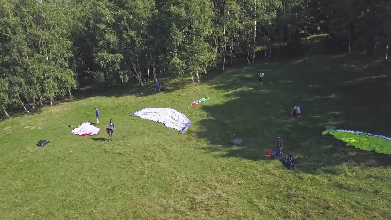 Paragliders standing on the side of a hill waiting for good flight conditions