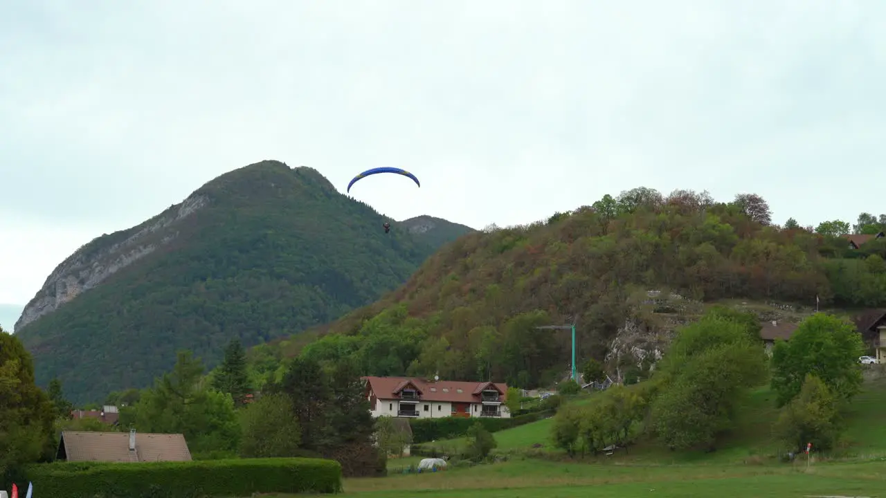 Paraglider Lands in the Field near the Lake Annecy on a Cloudy Day