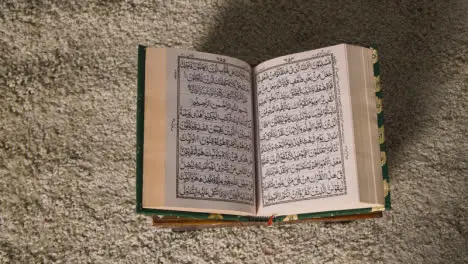 Overhead Shot Of Open Copy Of The Quran On Stand At Home