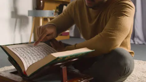 Muslim Man At Home Sitting On Floor And Reciting From The Quran 3