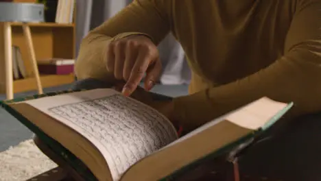 Muslim Man At Home Sitting On Floor And Reciting From The Quran 4