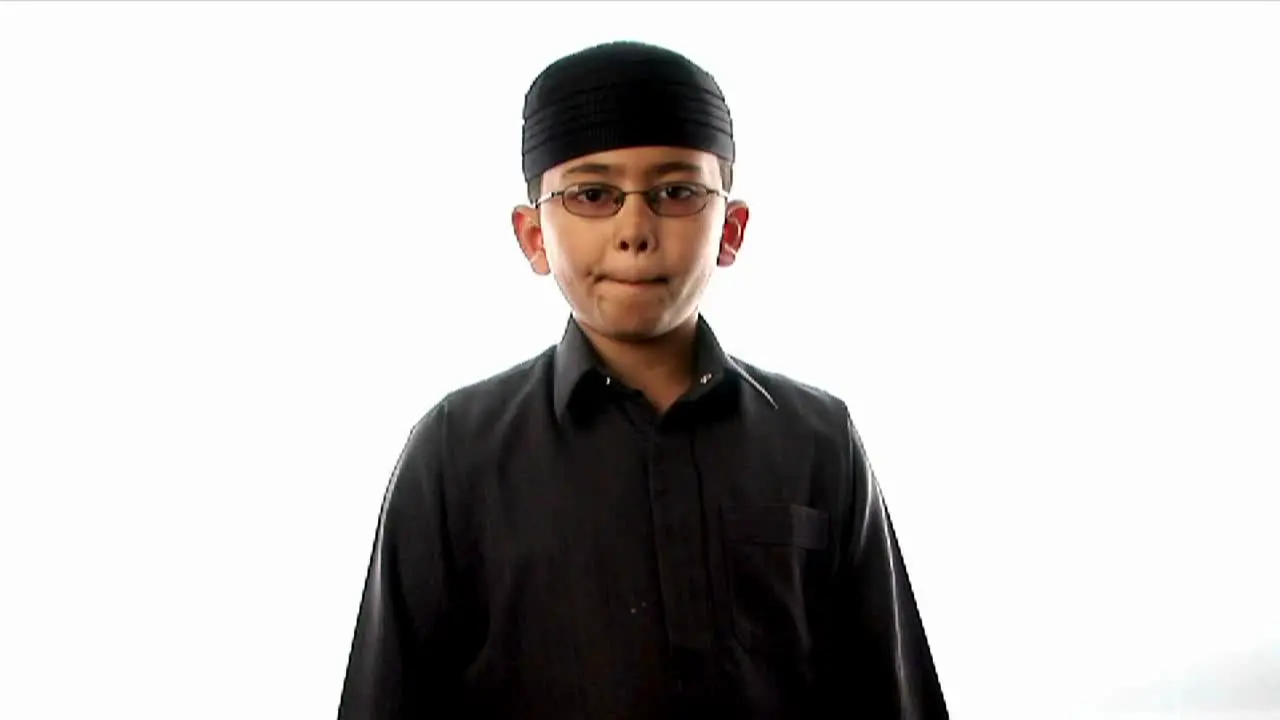 A young boy prays while wearing a tight fitting hat